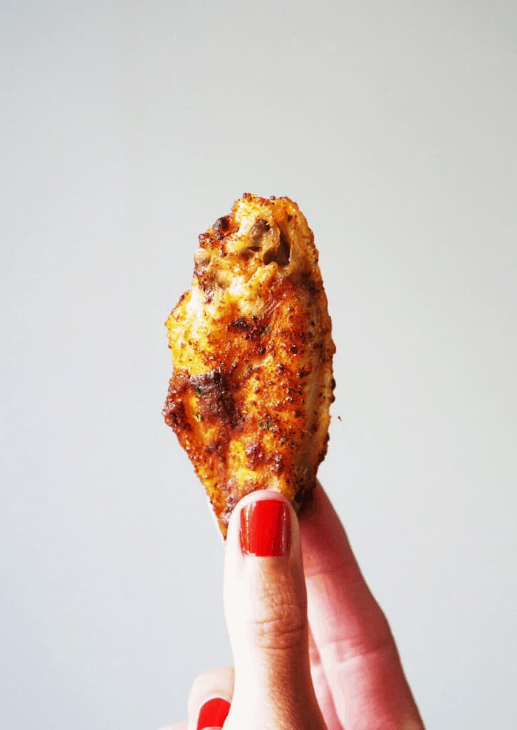 hand holding up a chicken wing