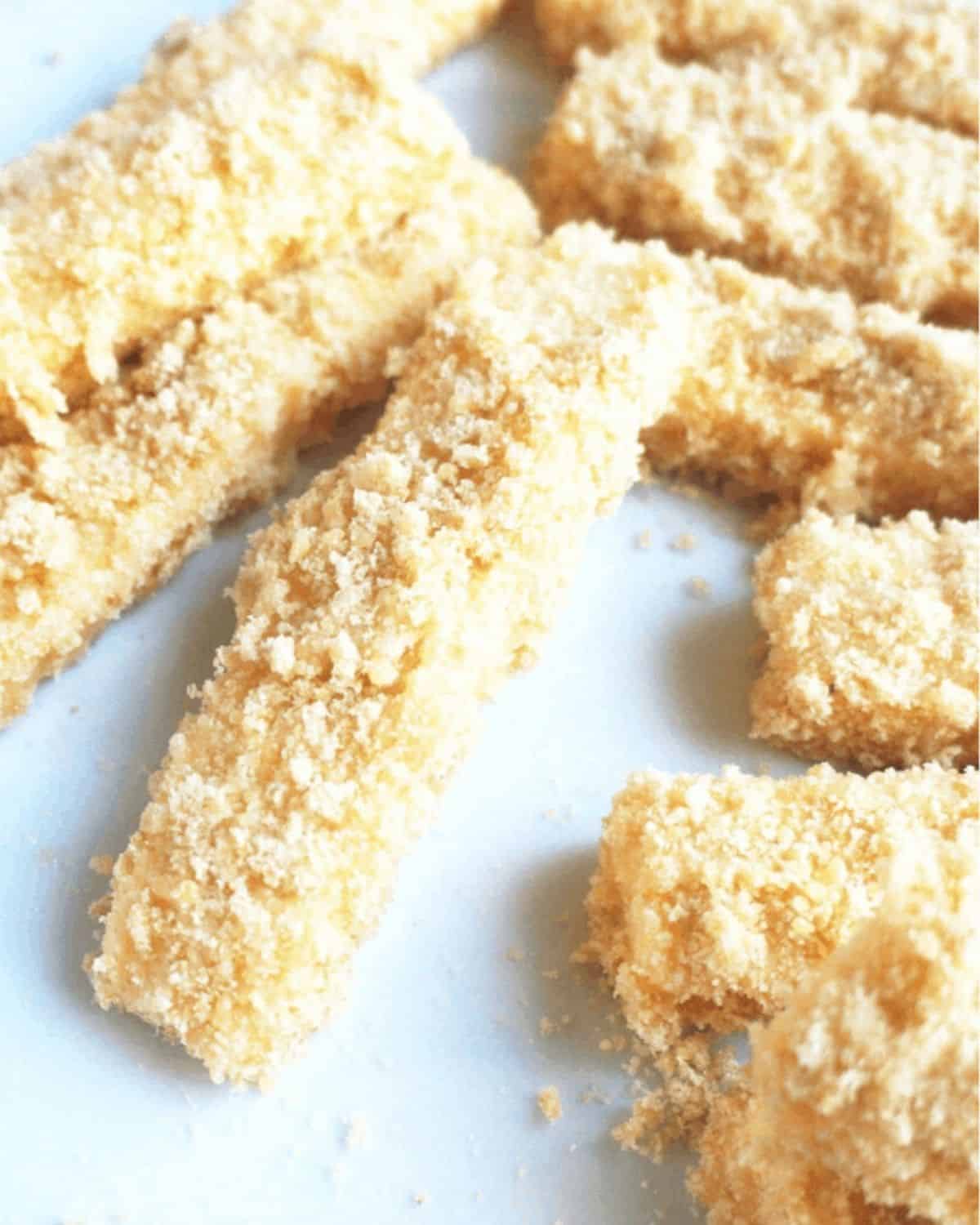 The strips of cheese coated in the pork rinds and ready to fry.
