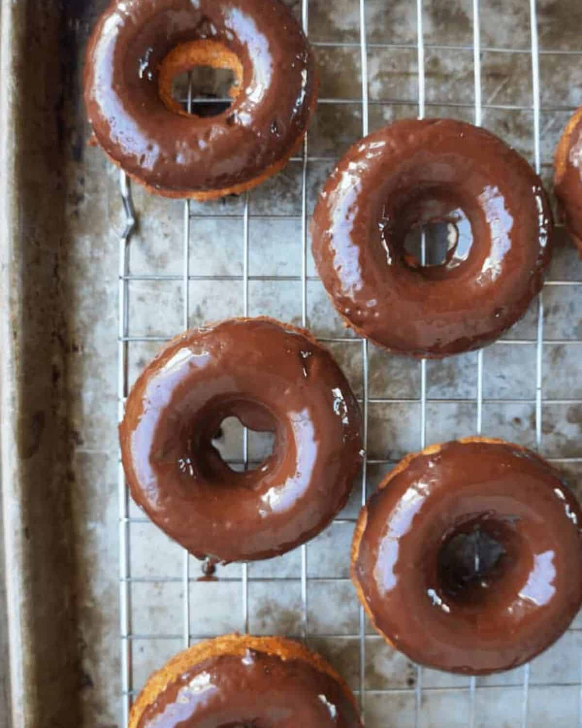 four baked dougnuts covered in chocolate glaze on a wire rack