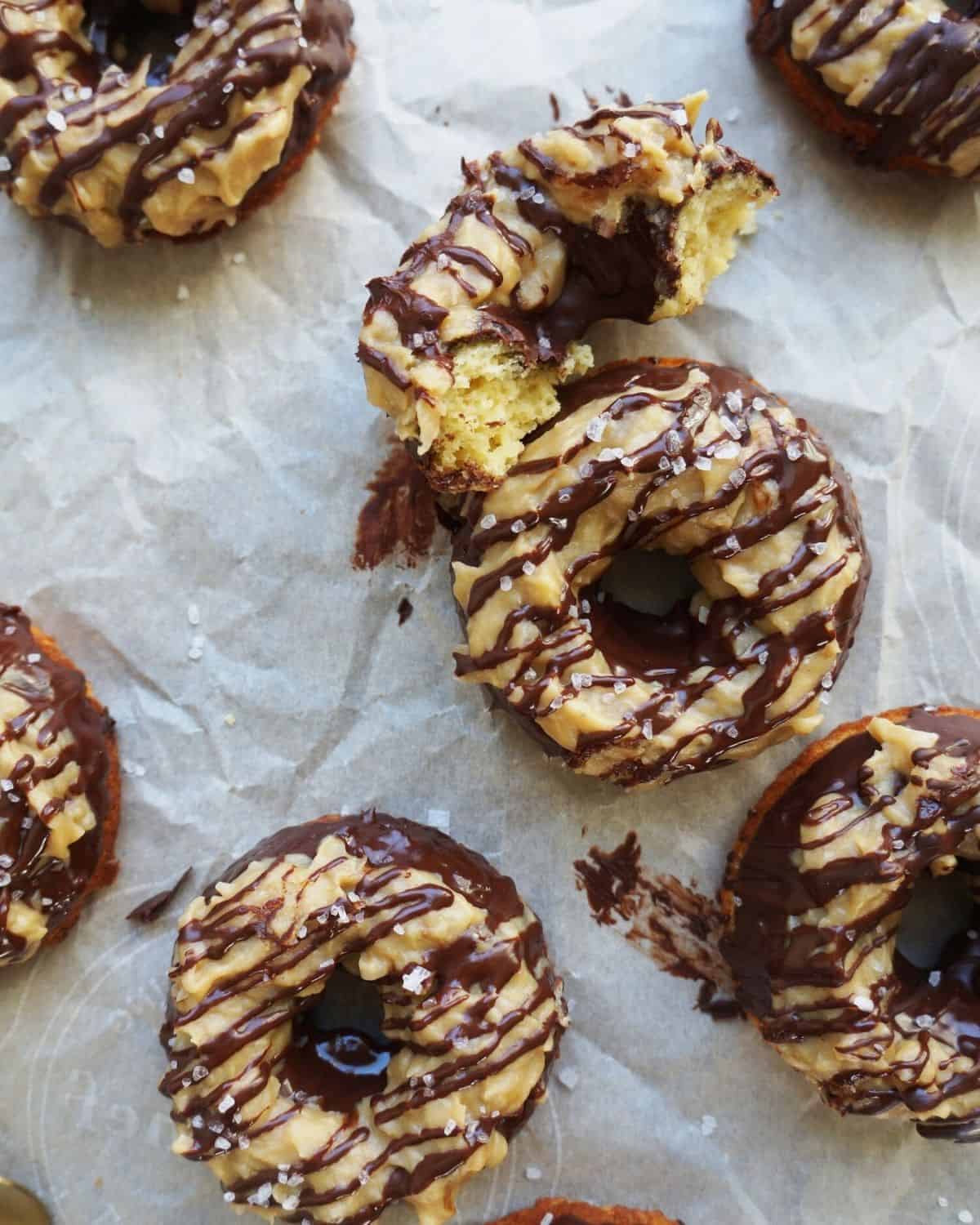 close-up of a caramel and chocolate keto donut torn in half surrounded by four other ones