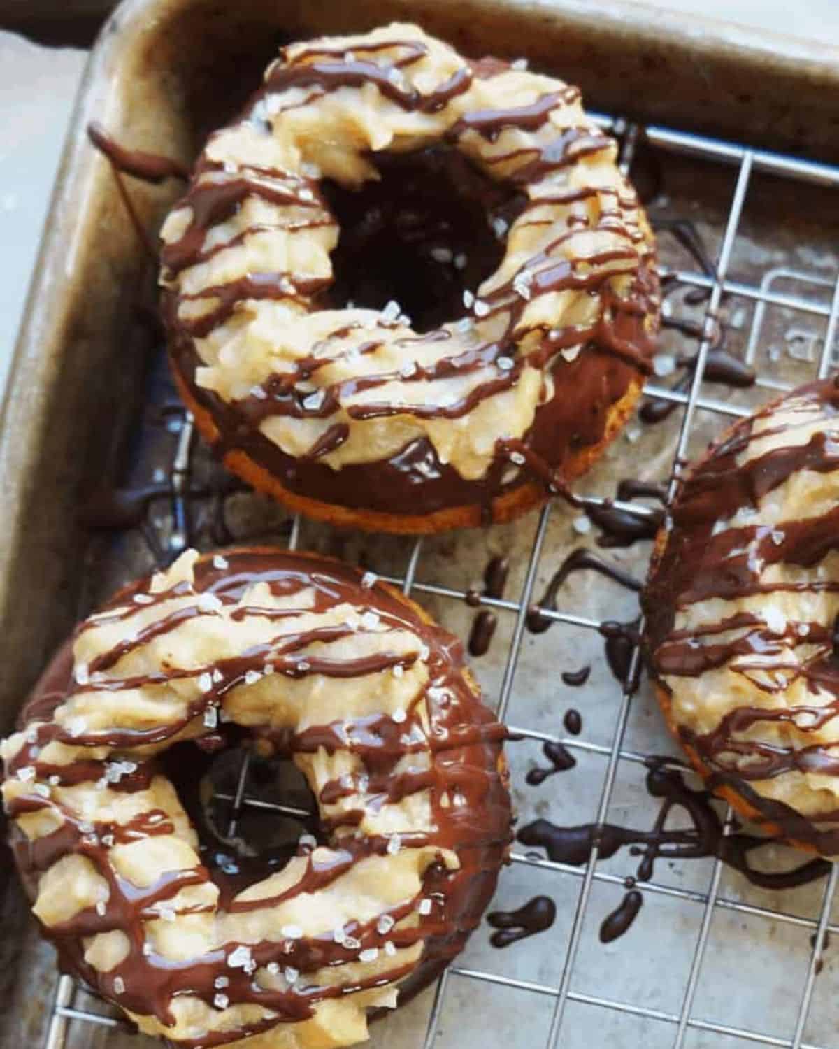 close up of two donuts on a wire rack with caramel topping